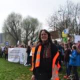 Menschen protestieren mit Bannern auf einer Wiese.