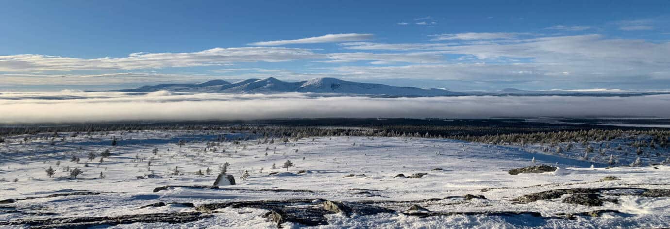 Verschneite Winterlandschaft mit Bergen im Hintergrund.